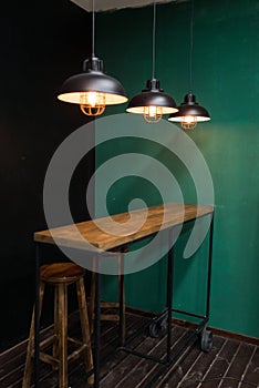 Bar rack on wheels in the kitchen with hanging lights and wooden bar stools against the backdrop of green and black walls