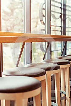 Bar stools stand in a row along the window in a cafe