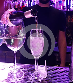 Bar wine glasses barman pouring wine from the bottle for