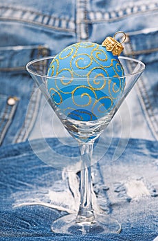 Bar winter season cocktail menu. Winter cocktail drink concept. Alcohol cocktail glass christmas ball ornament on denim