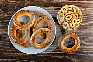 Baranka with poppy in blue plate, bread rings in bowl on wooden table. Top view