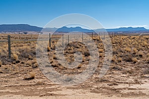 Barb wire fence along desert rural farmland in New Mexico