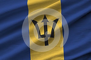 Barbados flag with big folds waving close up under the studio light indoors. The official symbols and colors in banner