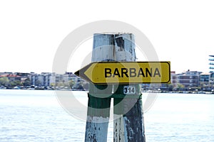 Barbana yellow pointer sign on a wooden pole in water