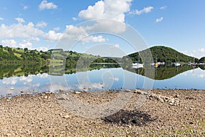 Barbecue ashes by beautiful lake on calm idyllic summer morning with cloud reflections