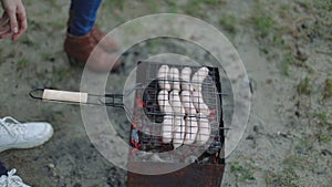 Barbecue browned sausages on the hot grill, a person turn and put upon brazier closeup