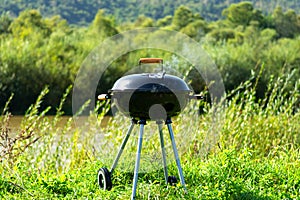 Barbecue, charcoal grill on the river bank. Relaxation, cooking in the fresh air. Summer rest