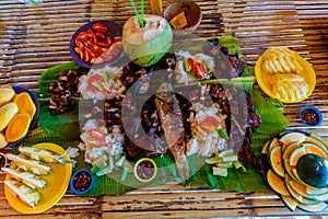 Barbecue of chicken, pork and fish is served on bamboo leaves with vegetables and fruits. Filipino cuisine