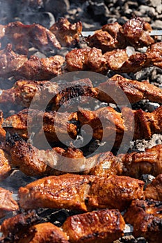 Barbecue cooking on skewers on charcoal grill with fragrant fire smoke. Close-up view,