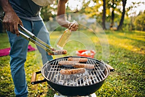 Barbecue. Croppe image of man flipping grilled sausage