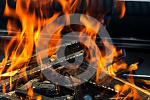 Barbecue grill pit with glowing and flaming hot open fire with red flame, hot charcoal briquettes and embers