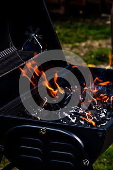 Barbecue grill pit with glowing and flaming hot open fire with red flame, hot charcoal briquettes and embers