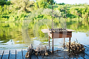Barbecue grill with wood on the river in beautiful nature, on a raft
