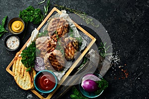 Barbecue: grilled meatballs wrapped in bacon with spices and sauce. On a stone board.