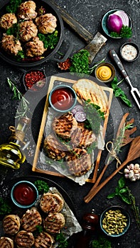 Barbecue: grilled meatballs wrapped in bacon with spices and sauce. On a stone board.