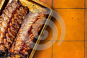 Barbecue grilled pork spare ribs. Orange background. Top view. Copy space