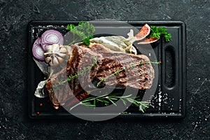 Barbecue. Grilled striploin steak with spices and rosemary. On a black concrete background.