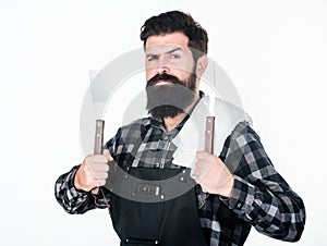 Barbecue master. Bearded hipster wear apron for barbecue. Roasting and grilling food. Man hold cooking utensils barbecue