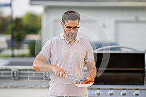 Barbecue master. Middle aged hispanic man in apron for barbecue. Roasting and grilling. Man hold cooking utensils