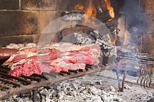 Barbecue. Meat cuts warming on the embers on an iron grill. Traditional Argentinian bbq.