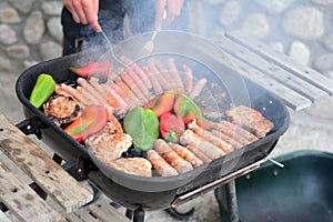 Barbecue with meat, sausages and peppers cooking on fire