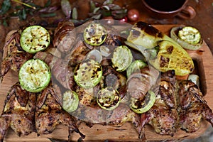 Barbecue in nature from quail, grilled vegetables, fried on a fire crossings on a wooden board with vegetables, fried zucchini on