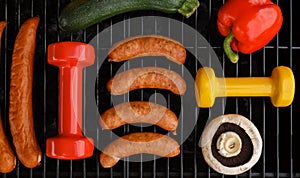 Barbecue party composition, healthy diet choice concept. With gym dumbbells on a grill.