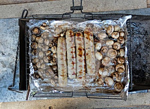 Barbecue sausages and mushrooms grilled on a fire grill. Cooking