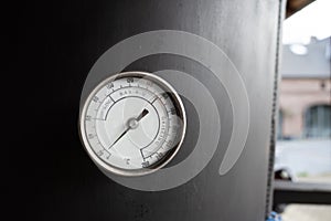 Barbecue, smoke and grill circular thermometer on black surface.