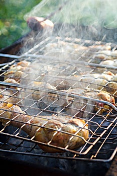 Barbecue smoked chicken legs preparing on metal grill at outdoor, selective focus