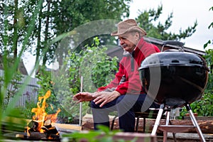 Barbecue time. European man in hat waiting for grilled food.