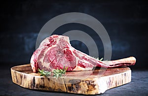 Barbecue Tomahawk Steak on dark background with herb prepared for grill photo