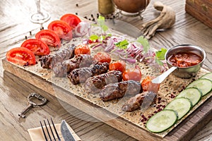 Barbecued kofta kebeb with onion and fresh tomato on lavash bread on wooden table