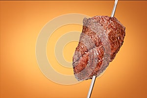 Barbecued Picanha barbecue with orange background. Also called churrasco photo