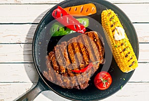 Barbecued rib eye beef steak with corn on the cob