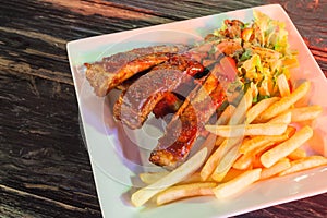 Barbecued ribs with french fries on wood table