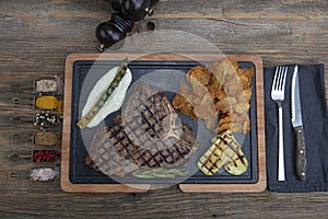 Barbecued t-bone steak seasoned with fresh herbs and marinade served with a cutting board in a steakhouse. Delicious restaurant