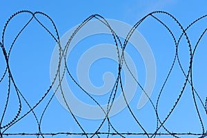 Barbed Razor Wire Military Security Fence Against Blue Sky