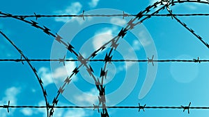 Barbed wire against blue sky and clouds