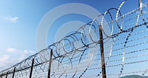 Barbed wire against a blue sky. Prison concept. Detail of New Fence with Barbed Wire