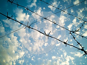 Barbed wire against the sky with clouds