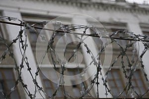 Barbed wire barrier with beautiful sky clouds and brick building behind the scene.