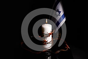 Barbed wire on burning candle and Israel flag on black background with space for text. Holocaust memory day