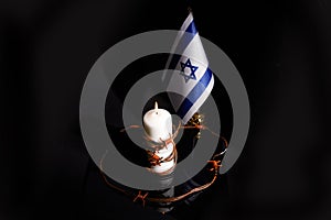 Barbed wire on burning candle and Israel flag on black background with space for text. Holocaust memory day