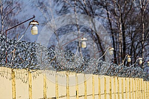 Barbed wire on a concrete fence with light lamps photo