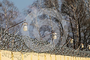 Barbed wire on a concrete fence with outdoor lamps photo