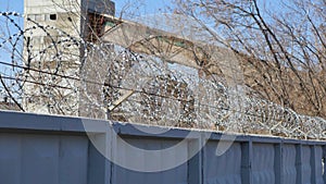 Barbed wire Egoza on the fence on the background of an industrial facility photo