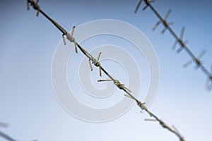 barbed wire through the fence against the blue sky. protection of private property.