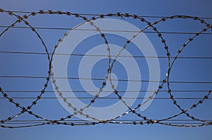 Barbed wire fence against clear blue sky photo