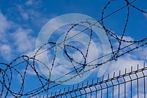 Barbed wire fence on background with blue sky and white clouds. Concept of freedom